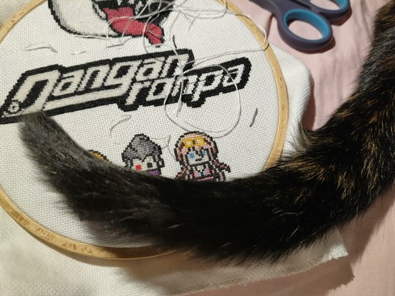 the same cross stitch while it was still being worked on. draped across the hoop is the tail of a tortoiseshell cat.