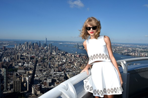 Taylor Swift standing on the Empire State Building with New York behind her