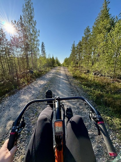 Riding a recumbent bike on a gravel road in the middle of a forrest.