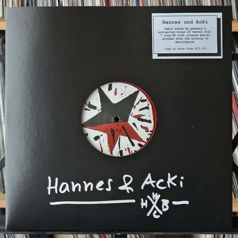 Ein schwarzes Albumcover mit einem runden Vinyl mit einem Sternmotiv in Rot, Schwarz und Weiß. Es ist eine Labelkarte beigefügt, die den Titel "Hannes und Acki" und Details über das Album zeigt, einschließlich seiner Beschreibung als Debüt.
