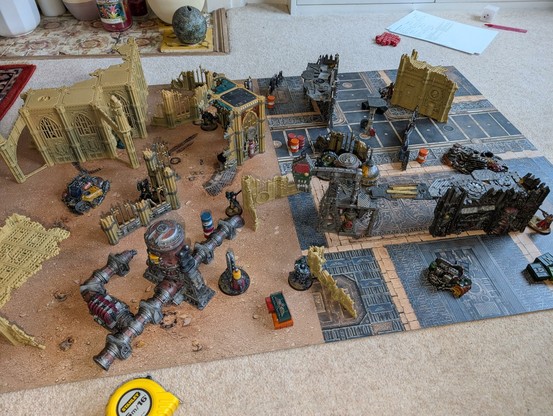 2 large detailed play boards covered in mostly painted terrain ranging from large ruined buildings to various bits of scatter crates and barrels. Somewhere in amongst all that to are 11 Citadel Miniatures, 5 Dark Angels and 6 Adeptus Mechanicus