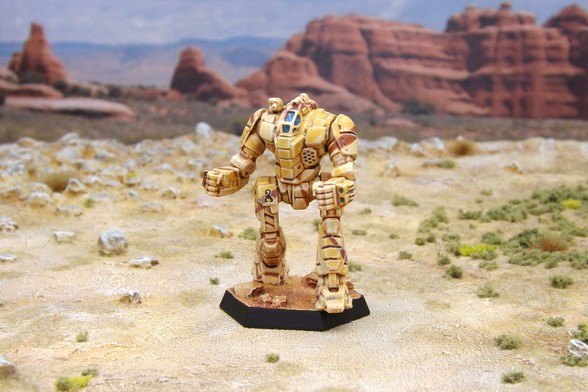 A painted miniature of a Exterminator 'Mech.  It is painted in tan and brown desert camo.  The black scorpion emblem of Clan Goliath Scorpion is on the right hip.  The miniature is photographed on desert terrain.