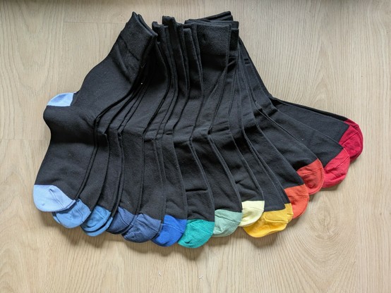 14 Paar neue schwarze Socken, alle mit leicht unterschiedlich farbiger Spitze und Ferse, regenbogenartig aufgefächert