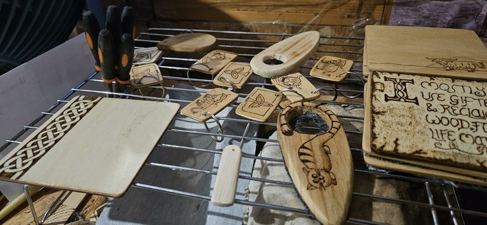 Various pyrography burned wooden items, including a coaster, keyrings and a door hanger with a cartoon cat burned onto it.