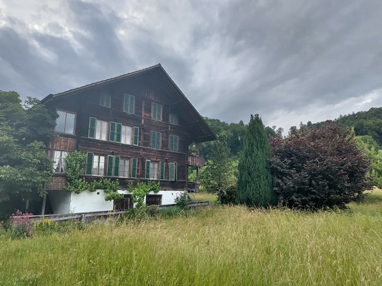 Traditional Bernese Oberland house with trees in various colours besides it.