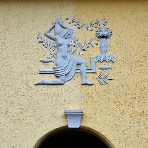 A picture of another stylized bas-relief, this one depicting a woman fetching water.