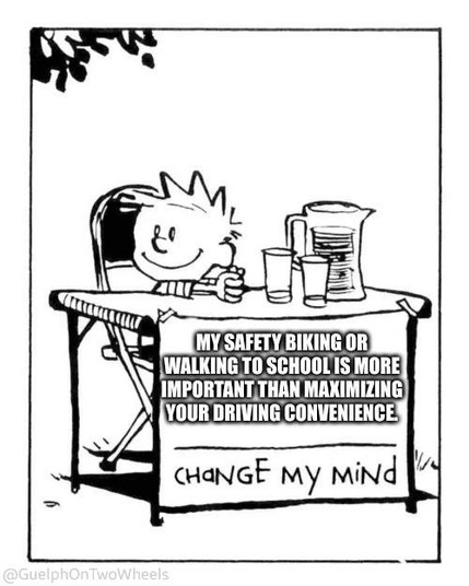 Calvin at a table with the sign, "my safety biking or walking to school is more important than maximizing your driving convenience."