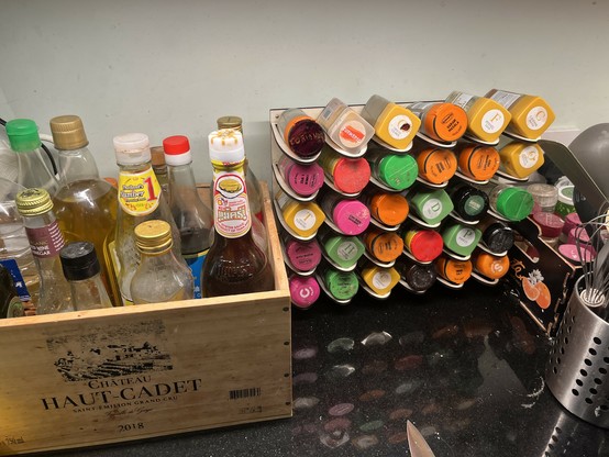 A laser cut spice rack full of spices, next to a wine crate with sauces