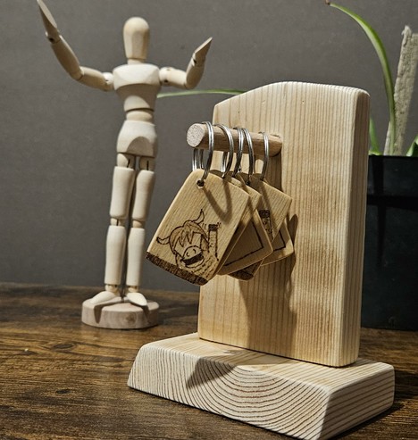A simple wooden stand with keyrings hanging off a wooden dowel "pole" sticking out of it.
