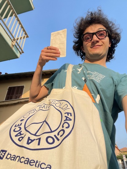 Un selfie in posizione strana che inquadra la mia faccia strana, il mio braccio che mostra la mia tessera elettorale, la tote bag di Banca Etica con lo slogan “coi miei soldi faccio la pace”, e la maglietta di libera con la citazione di Danilo Dolci: “Non esiste l’impossibile quando ci sono gli ideali di libertà e giustizia e l’impegno.”