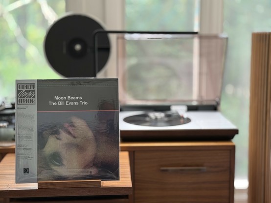 The Bill Evans Trio - Moon Beams LP cover.

A black band on top with the band and title. Below, a color photo of a blond woman's face and neck, horizontal.

The black LP plays on a vintage, restored Bang & Olufsen Beogram 4000 linear-tracking turntable to the right.