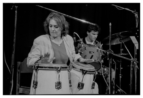 Black and white photograph of a percussionist with a drummer in the background. The percussionist looks very concentrated.