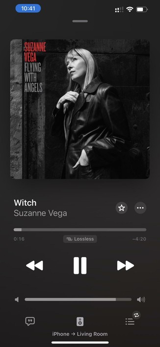 The image shows a music player interface displaying the song "Witch" by Suzanne Vega. The album cover features a black and white photograph of Vega in a leather jacket looking thoughtfully upwards, with the album title "Flying with Angels" prominently displayed.