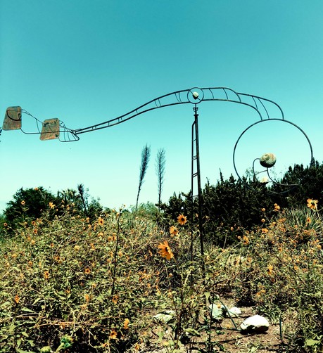 A kinetic wire framed sculpture in a field of yellow flowers