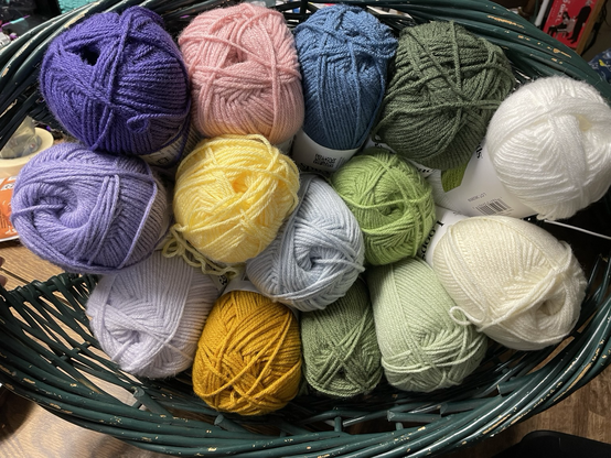 Several colors of yarn: three shades of purple from light to dark, four shades of greens, two shades of yellow, two shades of bleu, a pink, and two shades of white.