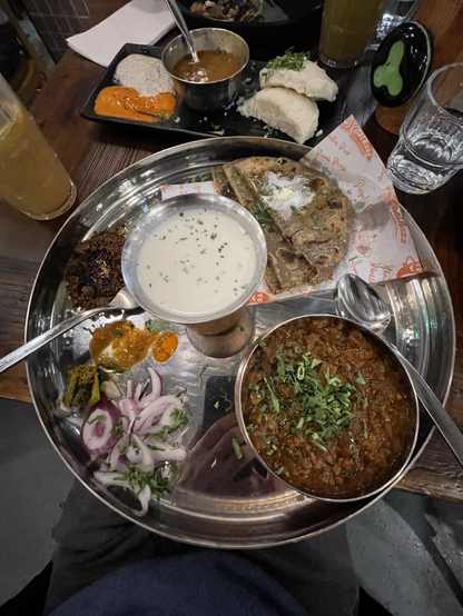 A platter containing spiced smoked eggplant with millet chapati, pickles and spiced & salted buttermilk