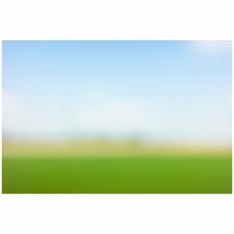 Abstract out-of-focus photo of a landscape. On the bottom is a green area and the top 2/3 are blue sky.
