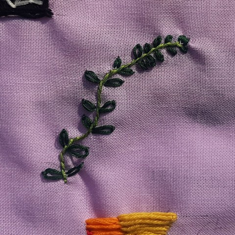 Broderie d'un plant de menthe en vert sur un tissu violet pale