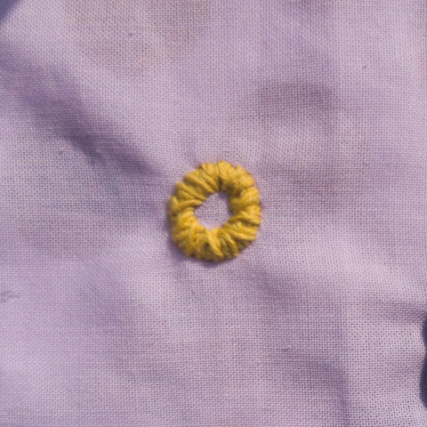 Broderie du motif bigouden pour le soleil en jaune sur tissu violet