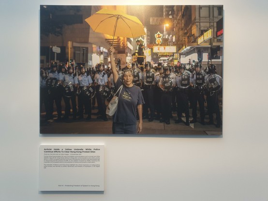 Photo of protests against Hong Kong's new security law showing a lone demonstrator holding up a yellow umbrella in front of a line of heavily protected police.