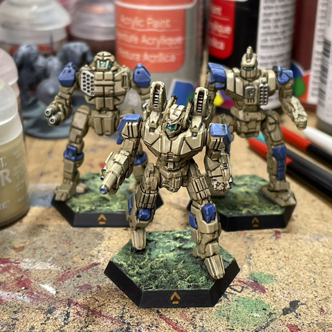 Phoenix Hawk miniature painted tan with blue accents in front of similarly painted Trebuchet and Centurion miniatures