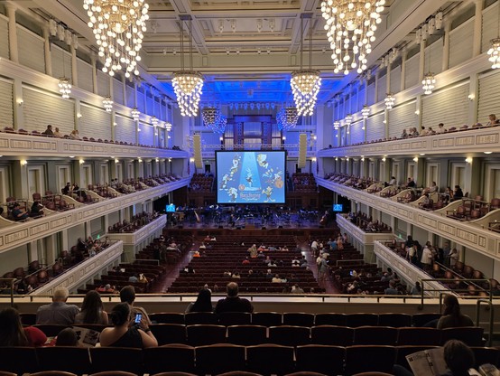 Wide angle shot of the Nashville orchestra hall from the rear mid tier. There's a huge screen featuring Looney Tunes characters and the legend,  Warner Bros. Discovery Presents Bugs Bunny At The Symphony