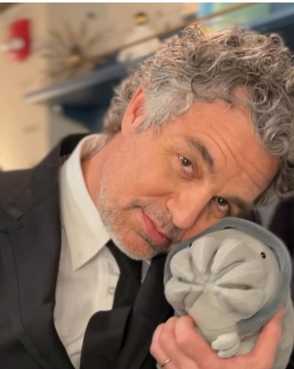 Mark Ruffalo posando con un peluche, sonriendo y vistiendo un traje elegante.