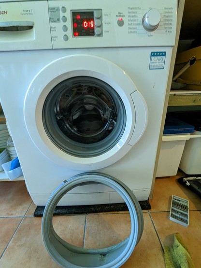 Eine Waschmaschine mit Bullauge. Programm läuft, Restlaufzeit 15 Minuten. Davor ein grauer Gummiring - die alte Türmanschette