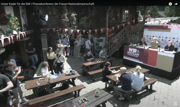 Rechts das Podium mit Bundestrainer, Geschäftsführerin und Pressesprecherin, links einige Picknickbänke mit einzelnen Journalist:innen, das ganze ist ziemlich trostlos.