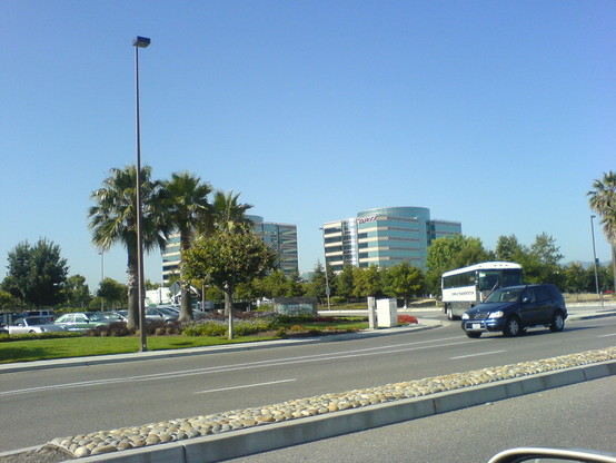 Two tall buildings. A bus exiting from parking lot.
