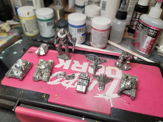 The top of my wet palette, containing some recently cleaned miniatures.  The rear row is a Hetzer wheeled assault gun, a Banshee battlemech, a Mechbuster fighter, and the bottom half of a Longbow battlemech.

In the front row are a Demolisher tank, a Zhukov tank, two Savannah Master hover tanks, a Striker light tank, a Seydlitz aerospace fighter, and a Merkava tank.  All of them are nice and shiny, having been freshly polished to await painting, possibly for quite a while.