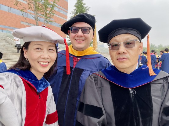 Three professors in academic regalia pose for a photo.