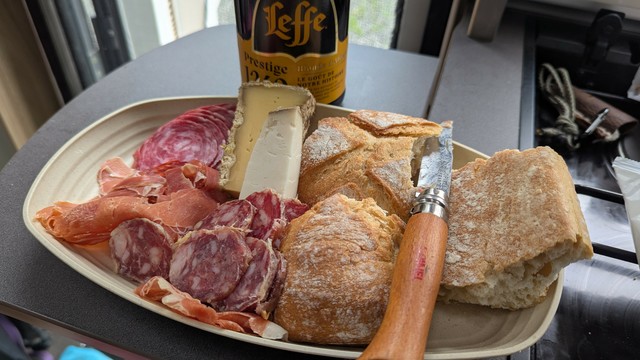 A plate of french bread, various sausages and cheeses (mostly local products) and a bottle of Leffe