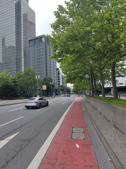 A red cycle lane without separation on a 3 lane one way road in a business district