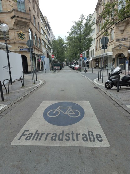 A cycling street in a city. A drawing on a street shows a bike pictogram and a text : fahrradstrasse