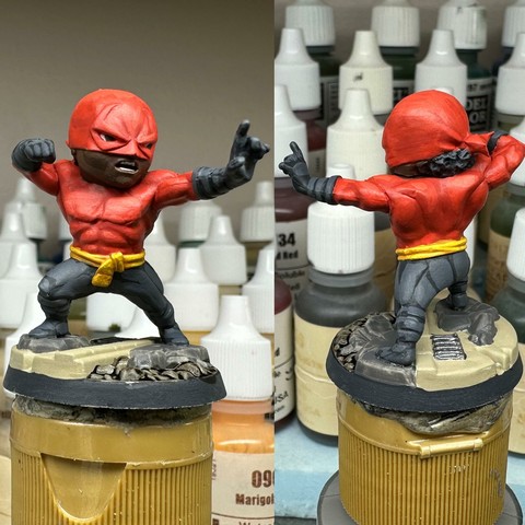 A black African superhero in a martial arts stance. His black pants, yellow belt, and red shirt and mask mirror the colors of the MPLA and Angola’s national flag.