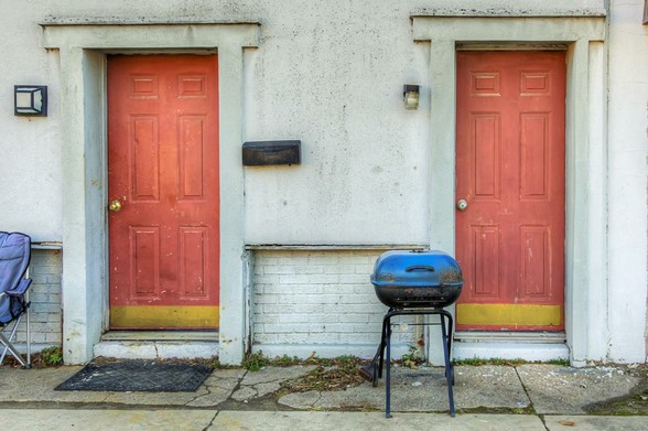 Grill Between 2 Doors

Two red doors stand side by side on a stucco wall, each with a small light fixture above them.