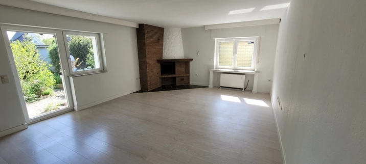 Bild zeigt Blick in das Wohnzimmer mit offenem Kamin und links den Innenhof (der gehört zur Wohnung dazu).
