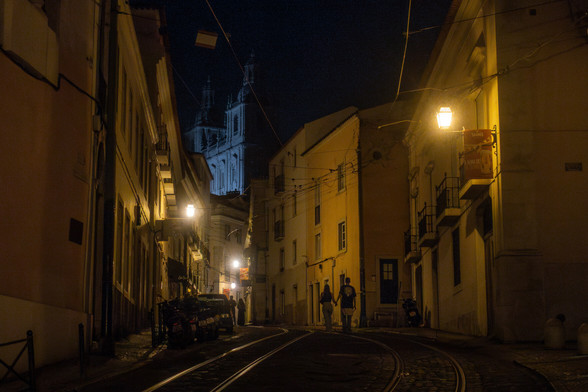 a couple walking down the street in Alfama neighborhood in Lisbon at 4am