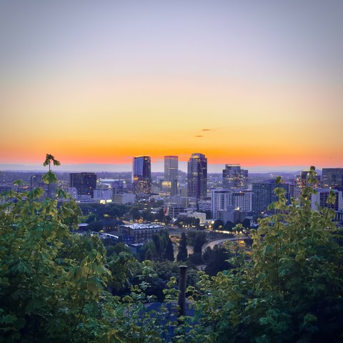 Downtown Portland sits under a blue and orange twilight sky on a mostly clear morning.