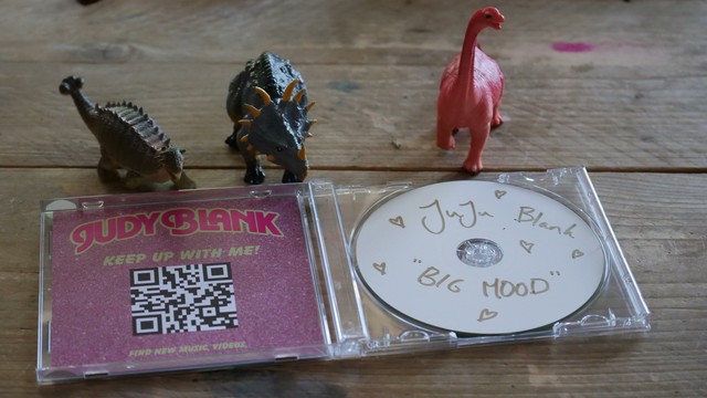 CD with handwritten label reading JuJu Blank "Big Mood" with lots of cute hearts drawn and a booklet with QR code