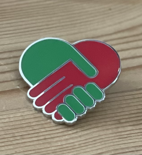 Speltje van hartje gevormd door een rode en groene hand die elkaar vasthouden.