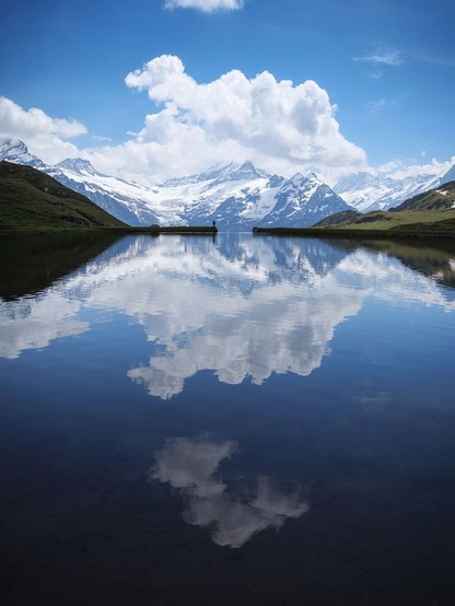 Das Bild zeigt eine sich in einer Wasseroberfläche spiegelnden Landschaft in den schweizer Alpen.