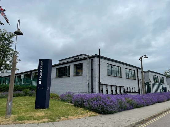 Photo of the entrance of Bletchley Park with lots of lavender growing in front of the concrete building.