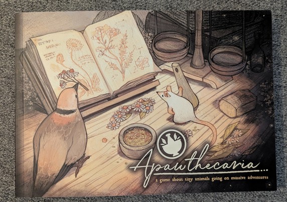 A small, horizontally printed book.
The cover is mostly in a sepia-toned old book style color and shows a little white mouse and a bird sitting on a wooden table in front of an opened book depicting several plants.

Scattered around them are several plant parts, a mortar and an old-fashioned, wooden scale. The mouse is holding the corresponding pestle next to her.

The name "Apawthecaria" is written in cursive and below it in printed letters "a game about tiny animals going on massive adventures."