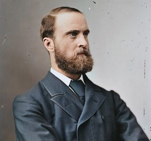 Colourised portrait photograph of Charles Stewart Parnell. He is wearing a blue suit and tie and has a full reddish beard.