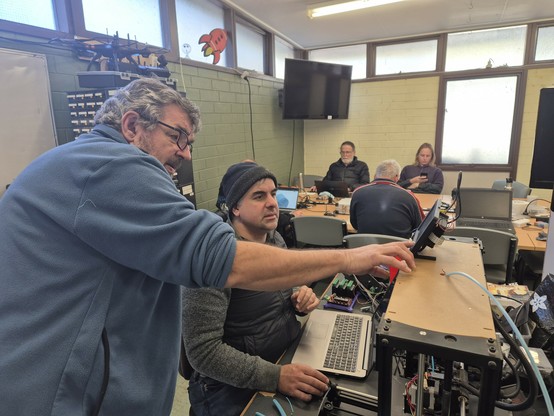 Two people in foreground collaborating on a 3D printer