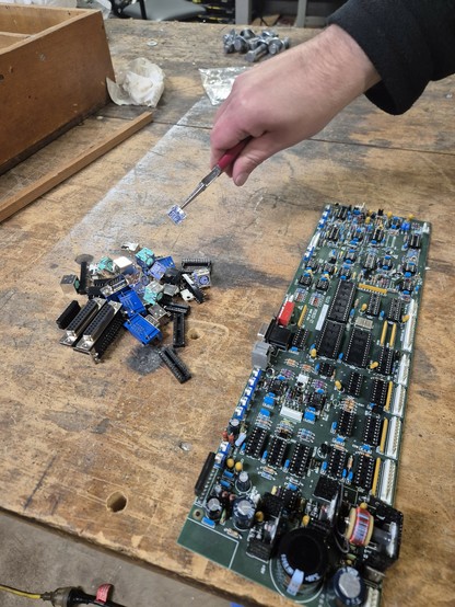 Assorted harvested electronic components on table next to PCB