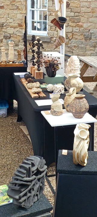 A display of ceramic sculptures under a gazebo. A stine building in the background