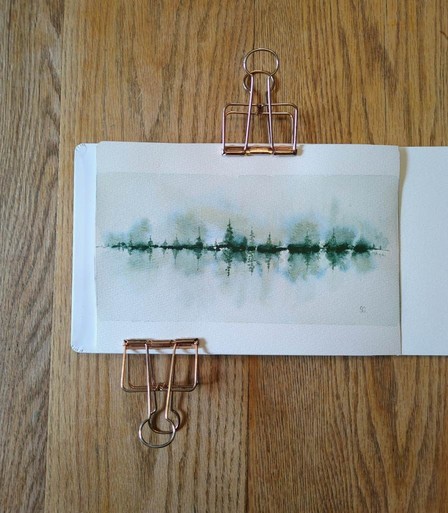 This is a Reflective Atmospheric Watercolor Landscape Painting in landscape orientation in an A5 sketchbook. The rectangular boundaries and smaller sized evergreen trees give a panoramic feel. The largest tree (and its reflection) is 1/3 of the total height of the painting. I used Daniel Smith Cascade Green for this experimental piece for its granulation and color splitting; it's made with raw sienna and phthalocyanine blue. With masstone of a dark yellow green at the tree line, some of the medium values are also yellow green with a distinct blue edge. Elsewhere medium and light values of raw sienna are visible.  The lightest value is minty green. The trees are tallest in the center and shortest on the sides. The overall feeling is the mistiness in the early morning.